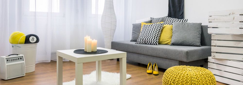 salon scandinave avec canapé gris, table basse blanche et pouf jaune