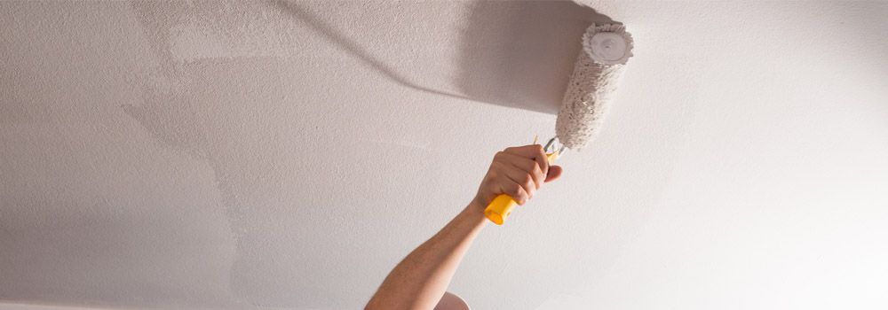 quelqu'un en train de peindre le plafond avec un rouleau