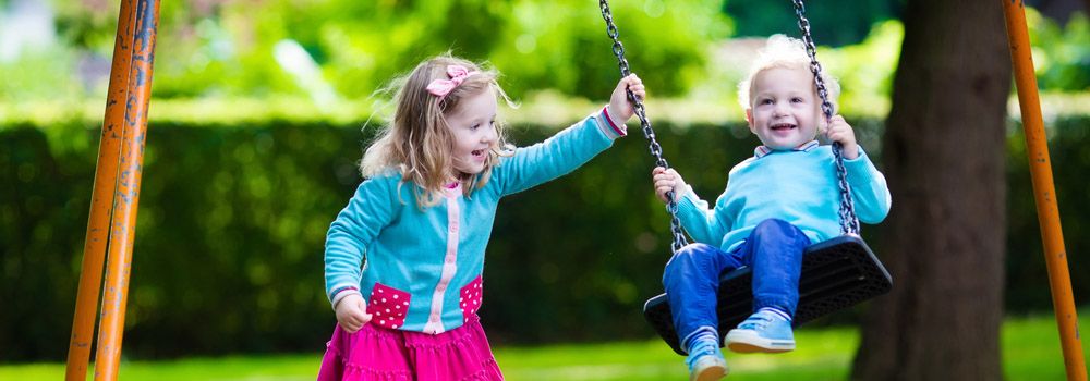 une petite fille et un petit garçon sur des balançoires