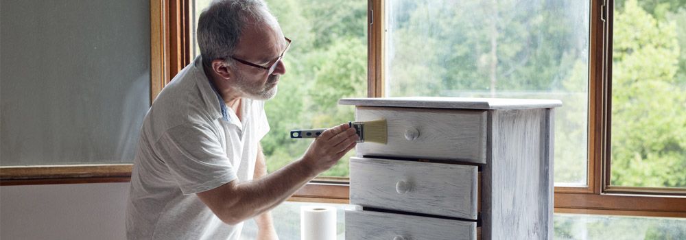 homme en train de repeindre une table de chevet
