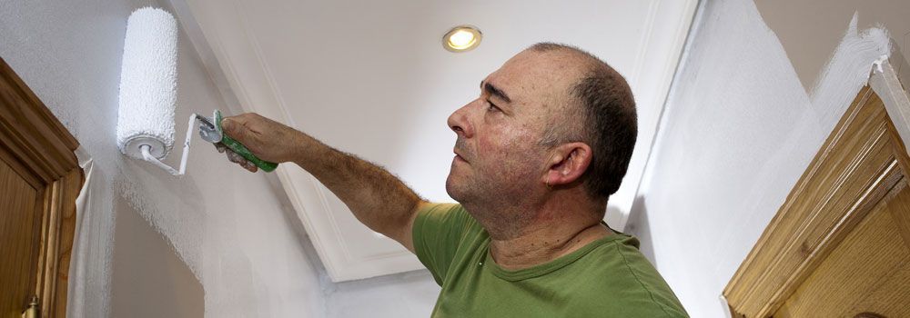 Homme peignant un mur en blanc