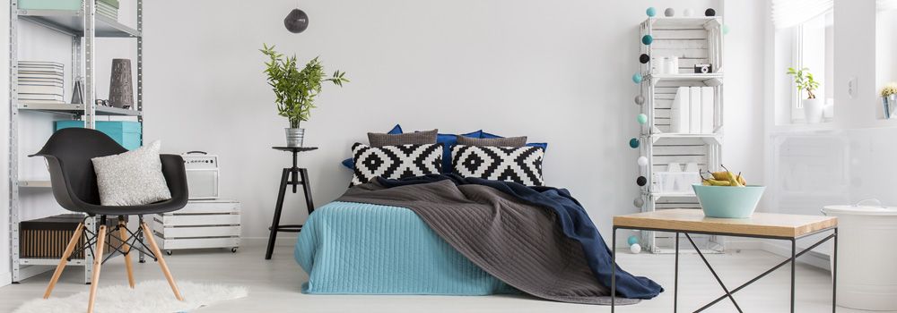 chambre : lit, table basse avec pied métallique et plateau en bois, fauteuil, étagère métallique